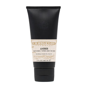 Black tube of amber hand cream on a white background
